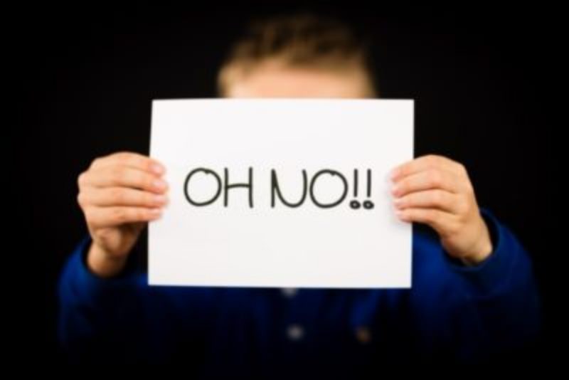 Person holding a sign that says "Oh No" with exclamation points