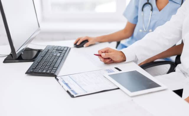 Two doctors looking at a computer and tablet