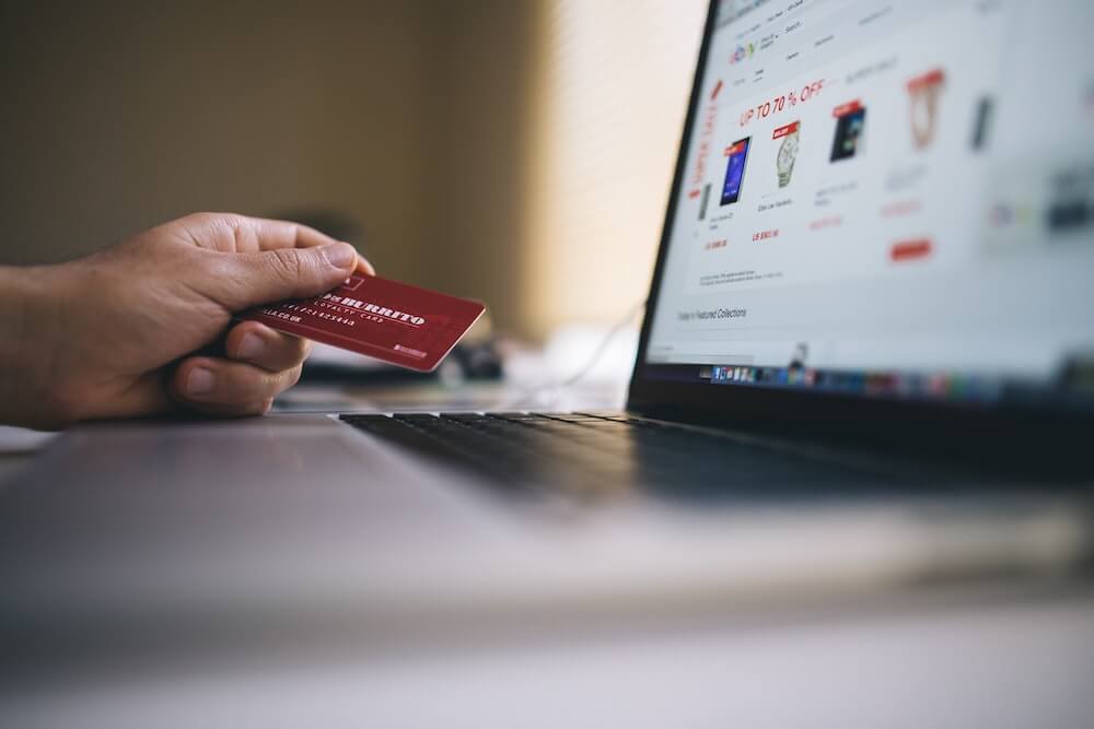 Person holding credit card while online shopping on laptop