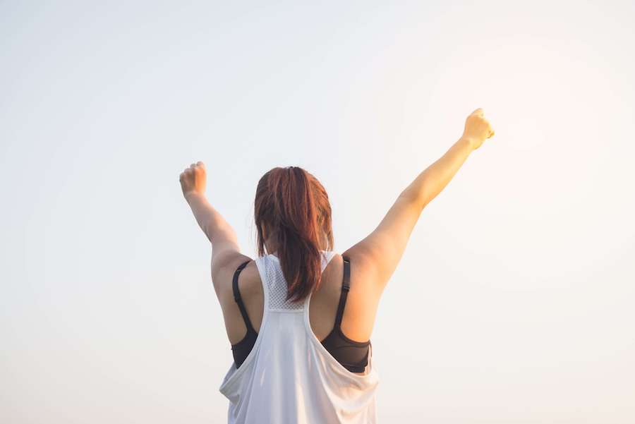 Woman reaching both arms up as if stretching