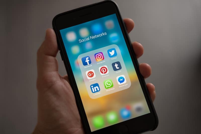 Hand holding a cell phone with social network app icons on the screen