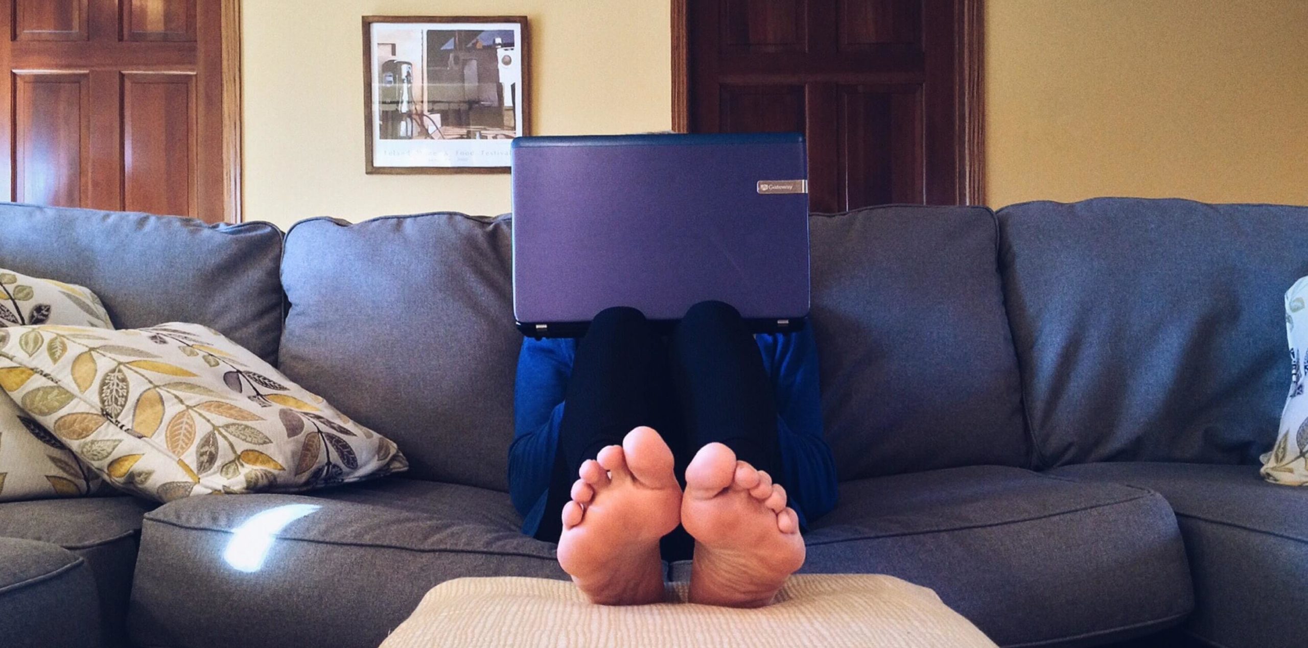 Person sitting on a couch with their feet up and a laptop open on their lap