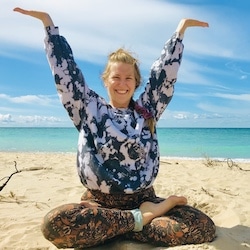 Photo of Megan doing yoga on a beach.