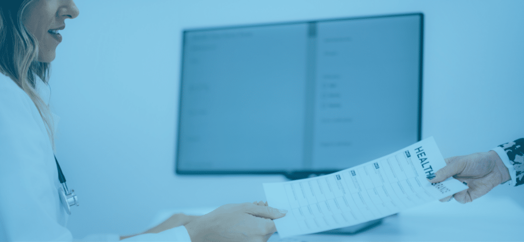 A doctor is holding a paper in front of a monitor