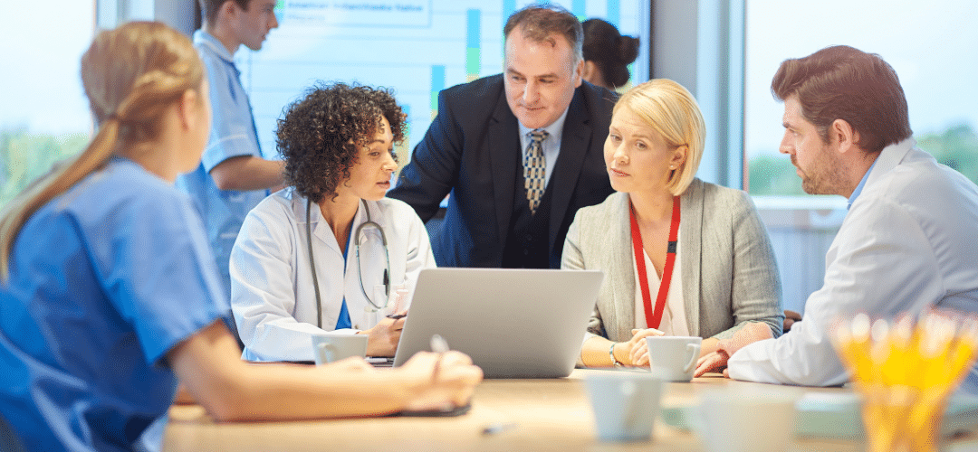 Medical professionals sitting around a table looking at a laptop