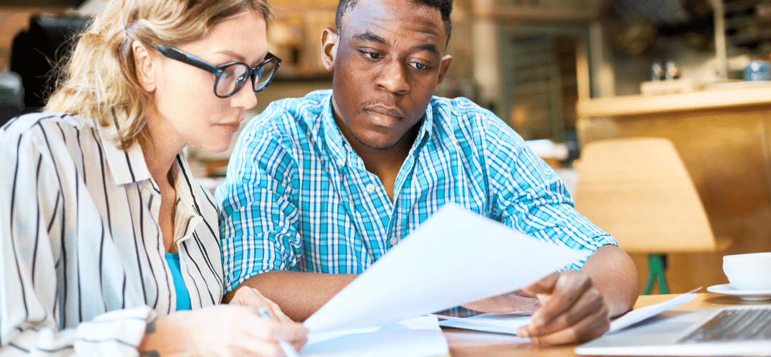 Two people sitting at a table reviewing SOC2 audit papers